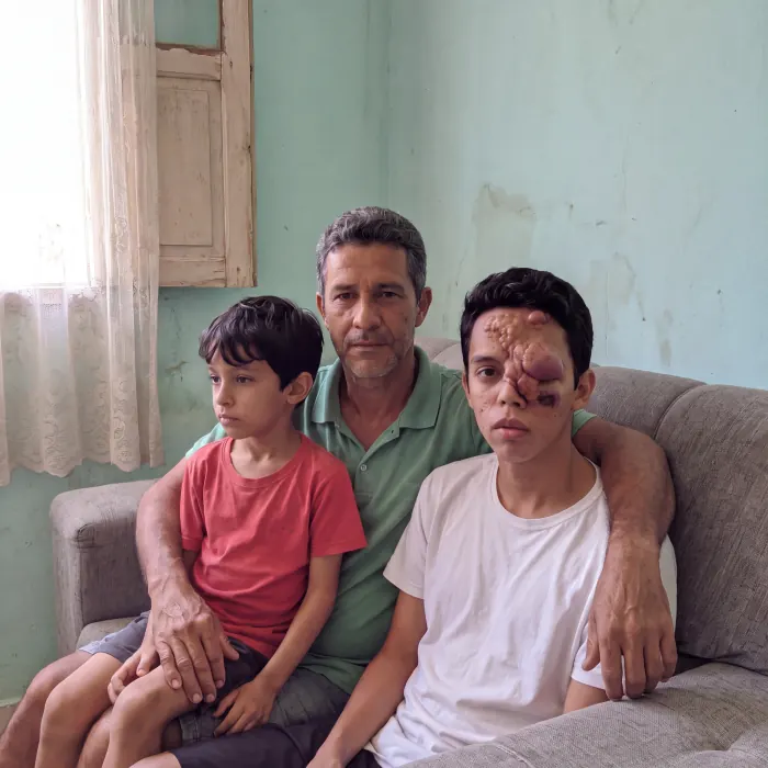 Pai sentado no sofá da sala com os dois filhos